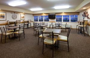 comedor con mesas y sillas y TV en GrandStay Hotel & Suites - Stillwater, en Stillwater