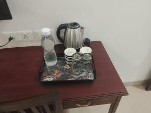 Una bandeja con una tetera y vasos sobre una mesa. en Tipsyy Inn Suites 020, en Gurgaon