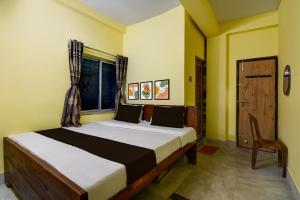 a bedroom with a bed and a window and a chair at Hotel O Lila Guest House in Sāntrāgāchi +20 photos