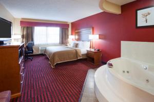 Habitación de hotel con cama y bañera en GrandStay Hotel & Suites - Stillwater, en Stillwater