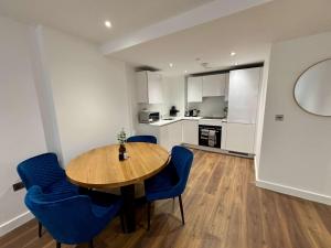 a kitchen and dining room with a wooden table and blue chairs at Luxury Modern 1 bed Central Bracknell in Bracknell