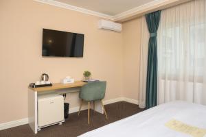 a hotel room with a desk and a tv on the wall at Pensiunea Casa Sturza in Bacău