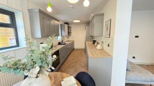 a kitchen with white cabinets and a wooden table at Crystal Palace Stylish Large Ensuite Double Room in Crystal Palace