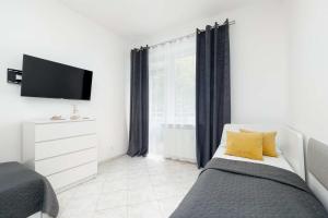 ein Schlafzimmer mit einem Bett mit gelben Kissen und einem TV in der Unterkunft Comfortable Studio for 3 People with Parking in Kołobrzeg by Noclegi Renters in Radzikowo