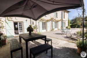 a table and two benches in front of a house at La demeure de zoé in Castelbiague