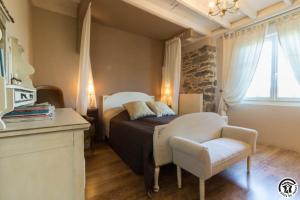 a bedroom with a bed and a chair and a window at La demeure de zoé in Castelbiague