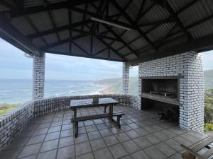 a patio with a table and a fireplace and the ocean at Blue Whale Resort in George