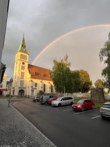 a rainbow over a church with cars parked in a parking lot at Apartmány Naxarův dvůr in Horažďovice +143 photos