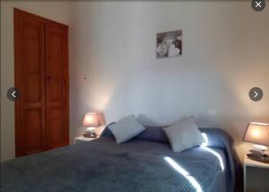 a bedroom with a bed with blue sheets and two lamps at Gîte Pic de Cluzel in Saurier