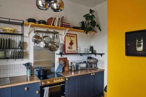 a kitchen with blue cabinets and a yellow wall at Mid-Century charm in the heart of Stroud in Stroud +30 photos