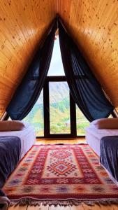 a room with two beds and a large window at Kvirike Cottage Kazbegi in Gorists'ikhe
