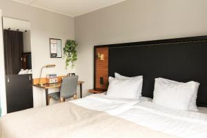 a bedroom with a large bed with a desk and a chair at Home Hotel Tapto in Stockholm