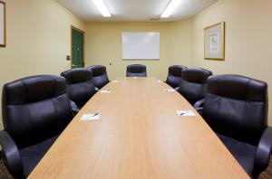 una sala de conferencias con una larga mesa de madera y sillas negras en GrandStay Hotel & Suites - Stillwater, en Stillwater