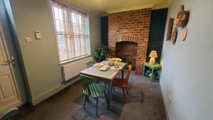 a dining room with a table and chairs and a fireplace at Cosy and comfy 2 bedroom cottage with parking to the rear and a short drive from Cannock town centre in Hednesford