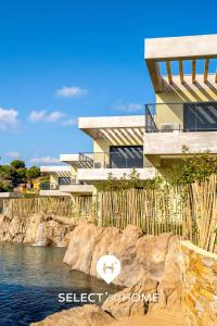une maison sur une falaise à côté d'une nappe d'eau dans l'établissement SELECT' - T2 avec vue - Piscine et parking privé - CAPNAT-B08, à Bormes-les-Mimosas