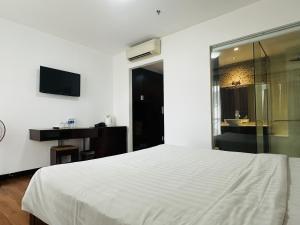 a bedroom with a white bed and a television at Dragon Sea Hotel in Da Nang