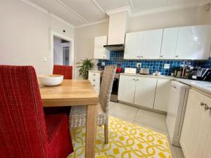 赫曼努斯Hermanus Self-Catering的厨房配有木桌和红色椅子 更多11张照片