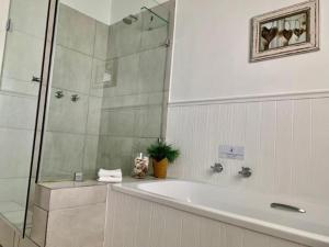 赫曼努斯Hermanus Self-Catering的浴室配有浴缸和玻璃淋浴房