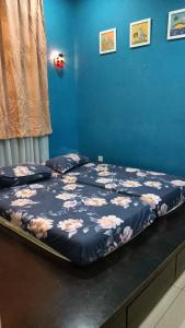 a bed in a bedroom with a blue wall at D Aida Homestay in Kampong Bukit Katil