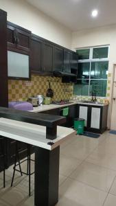 a kitchen with black cabinets and a counter top at D Aida Homestay in Kampong Bukit Katil