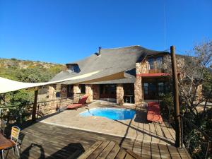a house with a pool and a patio with an umbrella at Sky Lodge in Hartbeespoort