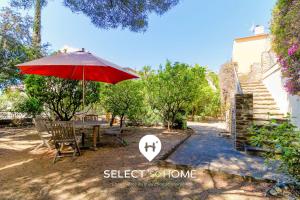a patio with a table and a red umbrella at SELECT'soHOME - Villa pour 8 personnes avec jacuzzi, vue mer et parking au coeur du Lavandou ! - VILLA MOUN PANTAI in Le Lavandou
