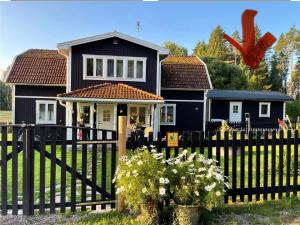 a black house with a fence in front of it at Stugan Karmaleily in Gävle