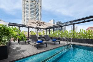 Una terraza en la azotea con piscina, sillas y sombrilla. en Citadines Connect Bertam Georgetown Penang, en George Town