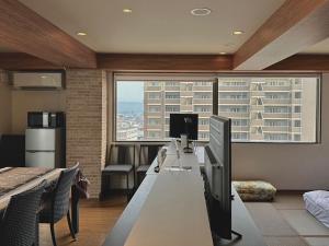 Una oficina con un escritorio con una computadora y una ventana grande. en DOMO Hotel 大津, en Ozu
