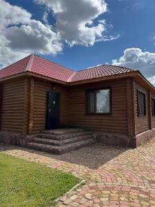 a wooden house with a red roof at Jansaya Resort база отдыха Жансая in Aleksandrovka