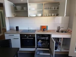 a small kitchen with white cabinets and a dishwasher at private Zimmer im Serviced Apartment - mit wöchentlicher Reinigung in Stuttgart