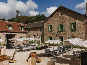 a large stone building with tables and chairs and umbrellas at Abbaye Des Vaux De Cernay in Cernay-la-Ville