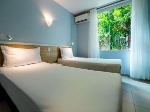 two beds in a hotel room with a window at ibis Styles Manaus in Manaus +253 photos