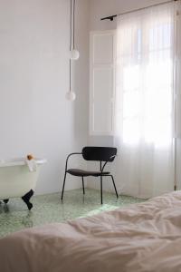 a bedroom with a chair and a bathtub next to a bed at Fragile Hotel in Ciutadella