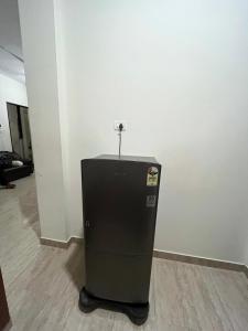 a black refrigerator in a room next to a wall at Luxe Loop in Mahabalipuram