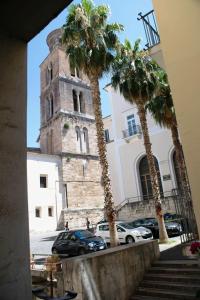 una torre dell'orologio con palme di fronte a un edificio di Il Guiscardo B&B a Salerno