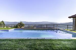 a swimming pool in the grass with mountains in the background at Casa De Basto in Celorico de Basto