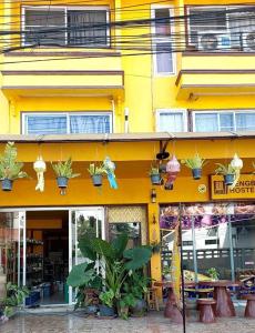 a yellow building with potted plants on the side of it at Dengba Hostel - Loikroh Chiangmai in Ban Hua Phrong