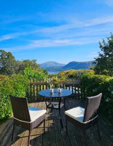 a table and two chairs on a deck with a view at Catbells Sunrise Cottage Borrowdale Lake District in Keswick