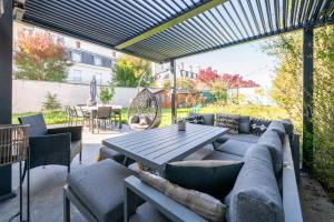 eine Terrasse mit einem Sofa und einem Holztisch in der Unterkunft L'Elbe in Serris