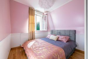 Schlafzimmer mit einem Bett mit rosa Wänden und einem Fenster in der Unterkunft L'Elbe in Serris