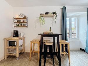 a kitchen with a table and stools in a room at Ty Breizh - Studio cosy au cœur de Dol-de-Bretagne in Dol-de-Bretagne