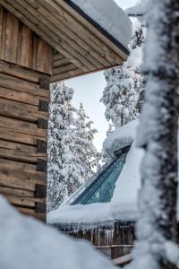 un edificio cubierto de nieve con árboles en el fondo en North Frontier Aurora Hut Kota, en Saariselkä