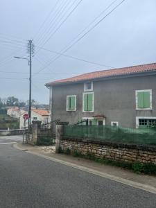 a house with a green fence next to a street at Duplex spacieux-2chambres-ideal vehicule electrique in Melle