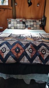 a bed with a colorful quilt on top of it at The Abel Tasman Treehouse in Marahau