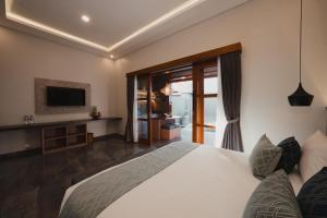 Un dormitorio con una cama blanca y un televisor. en Dikubu Belong, en Seminyak