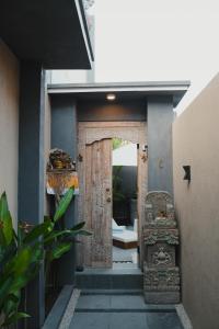 una entrada a una casa con una puerta de madera en Dikubu Belong, en Seminyak