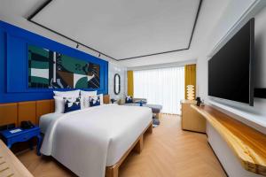 パトンビーチにあるTRIBE Phuket Patong by Accorの大きなベッドと薄型テレビがあるホテルの部屋