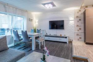 ein Wohnzimmer mit einem Tisch mit Stühlen und einem TV in der Unterkunft CBlue "Kaptain Carl", Terrasse, Grill, Strandnah in Graal-Müritz