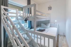 ein weißes Etagenbett mit einer Leiter in einem Zimmer in der Unterkunft CBlue "Kaptain Carl", Terrasse, Grill, Strandnah in Graal-Müritz